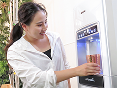 ウォーターサーバーの水をくむ女性の写真
